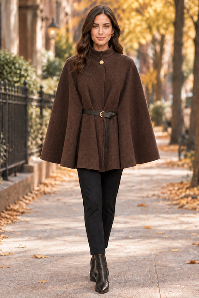 Female model wearing a short chocolate brown belted cape on an autumn city street